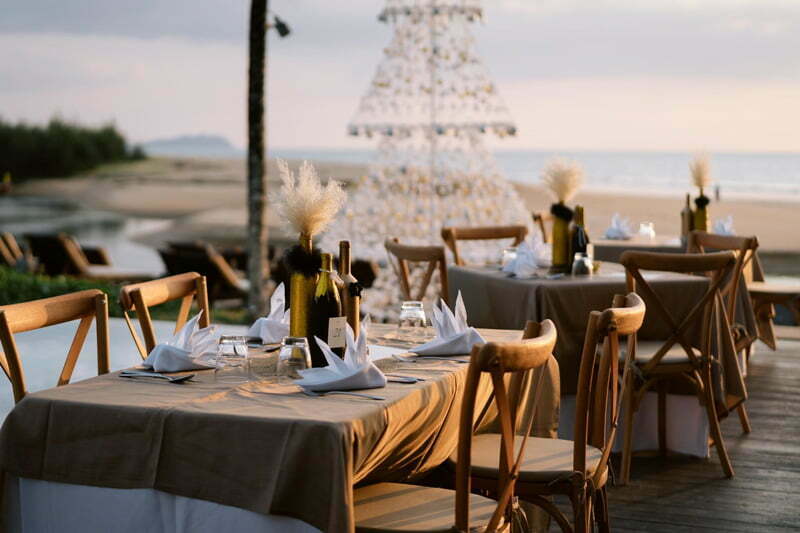Beautiful table setting overlooking the beach. With an ocean view and a tall light-up Christmas tree.